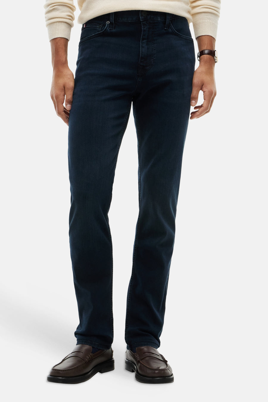 Dark blue straight-leg denim jeans with slim fit, worn by model in front view, paired with cream sweater and brown loafers