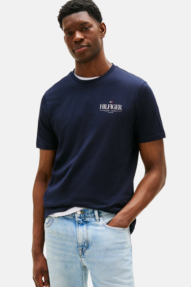 Blauw T-shirt met korte mouwen van TOMMY HILFIGER, gedragen met een verbleekte spijkerbroek en bruine leren loafers.