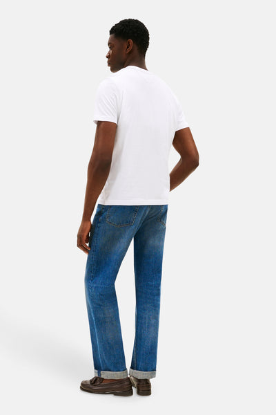 T-shirt blanc à manches courtes de TOMMY HILFIGER, porté avec un jean bleu retroussé et des mocassins marron.