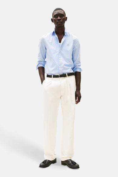 Chemise à manches longues bleue à motifs, de TOMMY HILFIGER, portée avec un pantalon et une ceinture noirs.