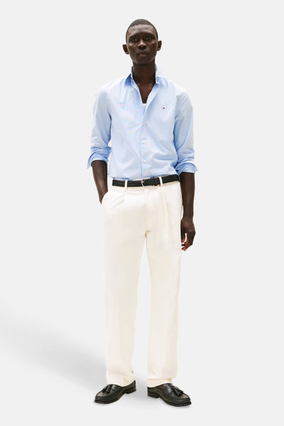 Chemise à manches longues bleue à motifs, de TOMMY HILFIGER, portée avec un pantalon et une ceinture noirs.