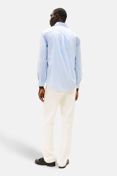 Chemise à manches longues bleue à motifs de TOMMY HILFIGER, vue de dos, portée avec un pantalon blanc et des mocassins noirs.
