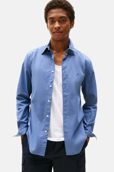 Chemise à manches longues bleue à pois de TOMMY HILFIGER, portée ouverte sur un débardeur blanc et un pantalon cargo marine.
