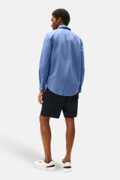 Chemise bleue à manches longues de TOMMY HILFIGER, à motif discret, portée avec un short noir et des baskets blanches