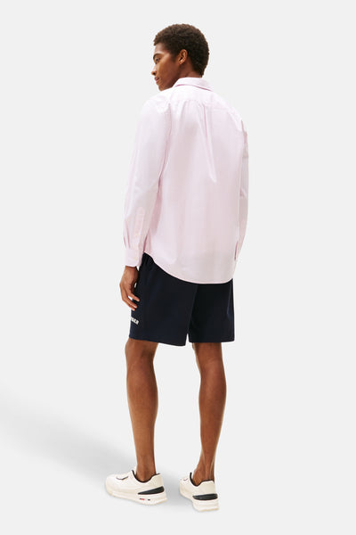 Chemise à manches longues rose à motif à pois, de TOMMY HILFIGER, portée avec un short bleu marine et des baskets blanches, vue de dos.