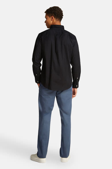 Chemise noire à manches longues de Tommy Hilfiger, coupe classique, avec pantalon bleu ardoise.