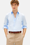 Chemise bleue à manches longues de Tommy Hilfiger avec un pantalon chino beige et une ceinture marron.