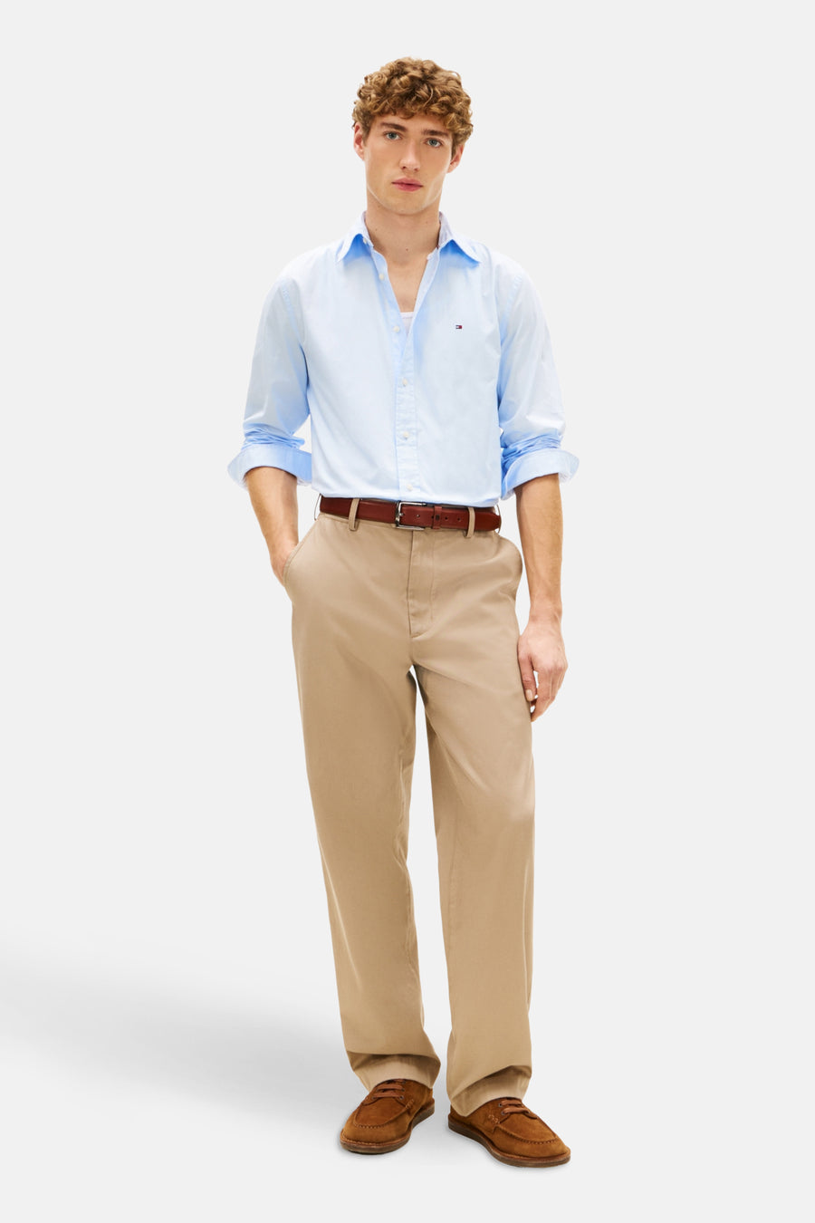 Chemise à manches longues bleue de TOMMY HILFIGER avec coupe classique, portée avec un pantalon et des mocassins marron.