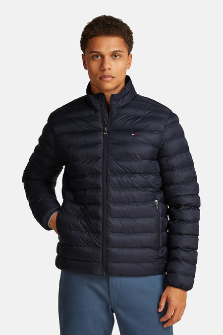 Veste courte bleue de TOMMY HILFIGER, doudoune légère à col montant avec fermeture éclair, portée par un homme.