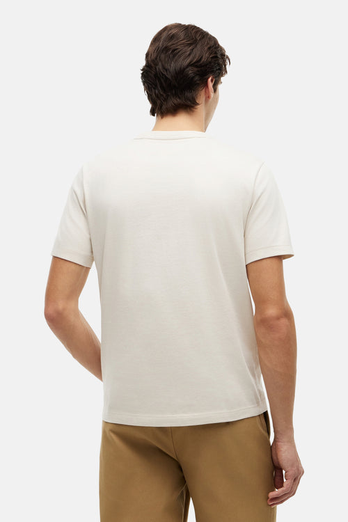 T-shirt écru de TOMMY HILFIGER, avec des manches courtes, porté avec un pantalon marron, vu de dos.