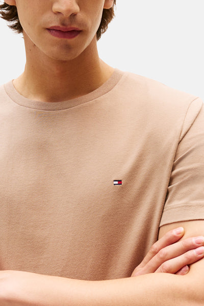 T-shirt beige à manches courtes de TOMMY HILFIGER, porté par un mannequin, avec le logo sur la poitrine.