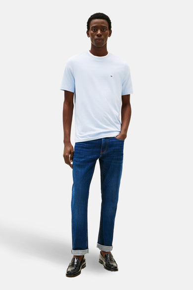 T-shirt bleu à manches courtes de TOMMY HILFIGER, porté avec un jean foncé à revers et des mocassins noirs.