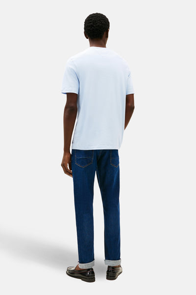 Blauwe T-shirt met korte mouwen van TOMMY HILFIGER, gedragen met een spijkerbroek en loafers, achtergezicht.
