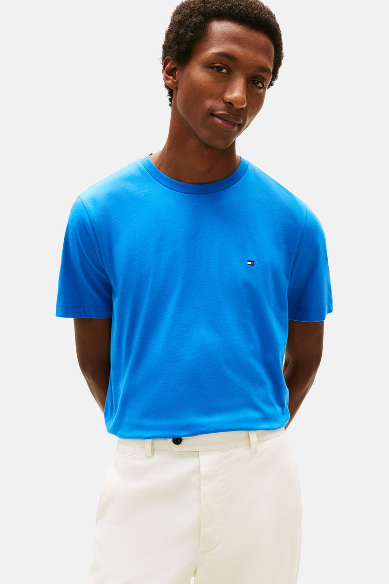 Blauw T-shirt met korte mouwen van TOMMY HILFIGER, gedragen met een witte broek en bruine bootschoenen.