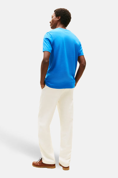 Blauw T-shirt (korte mouwen) van Tommy Hilfiger, van achteren gezien, gedragen met een witte broek en bruine schoenen