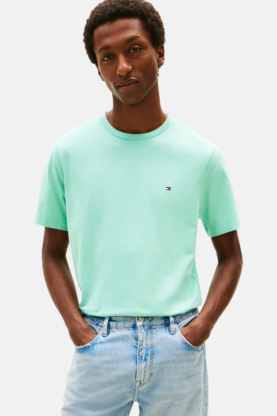 Lichtblauw T-shirt van TOMMY HILFIGER, met discreet logo, gedragen met een verbleekte spijkerbroek en bruine schoenen.