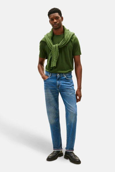 T-shirt à manches courtes vert de TOMMY HILFIGER, porté avec un pull noué et un jean bleu.