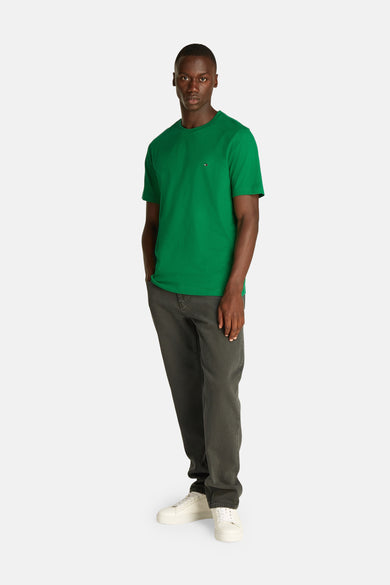 Groen T-shirt met korte mouwen van Tommy Hilfiger, gedragen met een grijze broek en witte sneakers.