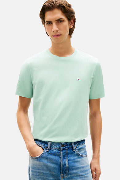 Groen T-shirt met korte mouwen van Tommy Hilfiger, gedragen met een spijkerbroek en witte sportschoenen.