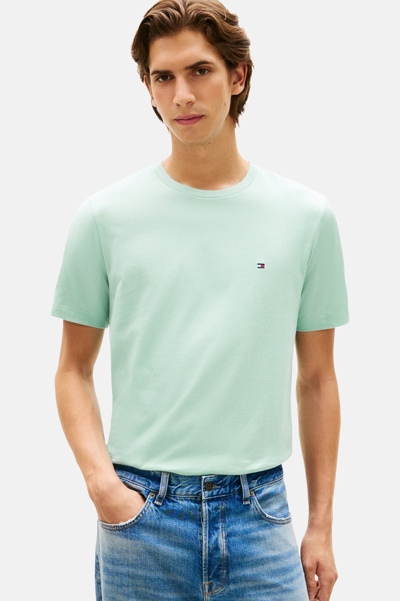 Groen T-shirt met korte mouwen van Tommy Hilfiger, gedragen met een spijkerbroek en witte sportschoenen.