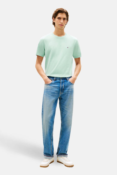T-shirt vert à manches courtes de Tommy Hilfiger, porté avec un jean et des chaussures de sport blanches.