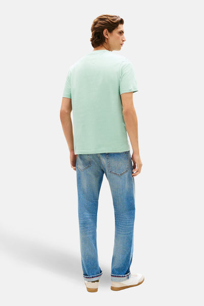 Groen T-shirt met korte mouwen van TOMMY HILFIGER, gedragen met een blauwe jeans en witte sneakers.