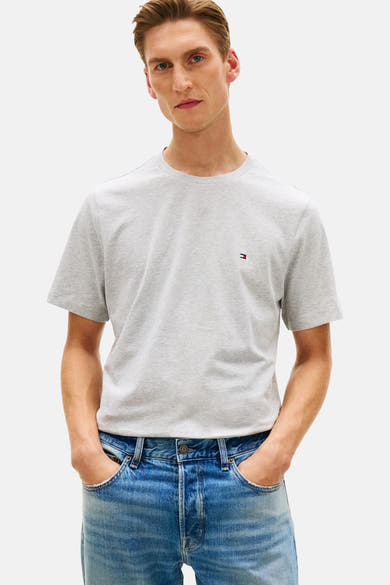 T-shirt à manches courtes gris de Tommy Hilfiger, porté avec un jean bleu délavé, les mains dans les poches.
