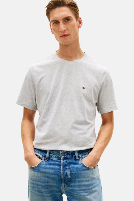 T-shirt à manches courtes gris de Tommy Hilfiger, porté avec un jean bleu délavé, les mains dans les poches.
