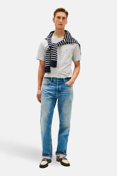 T-shirt à manches courtes gris de Tommy Hilfiger, avec un pull rayé bleu marine et blanc sur les épaules.