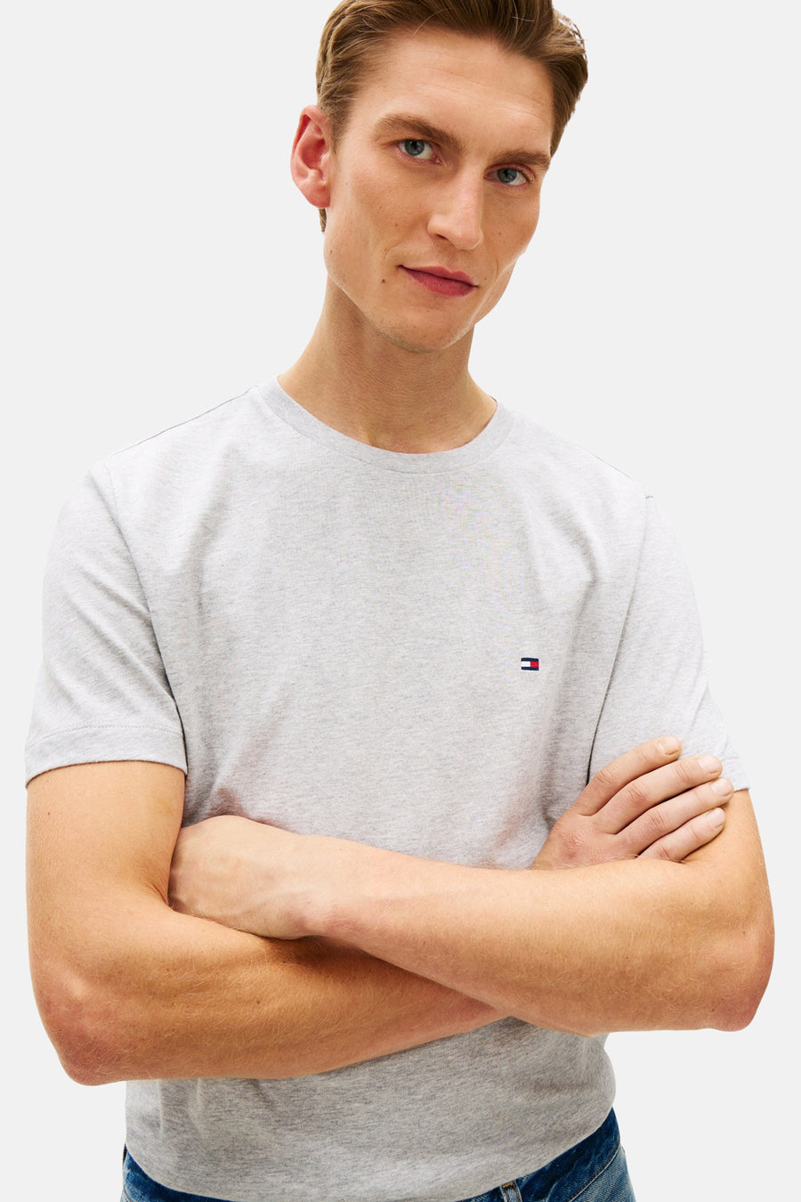 T-shirt gris à manches courtes de TOMMY HILFIGER, porté par un homme aux bras croisés.