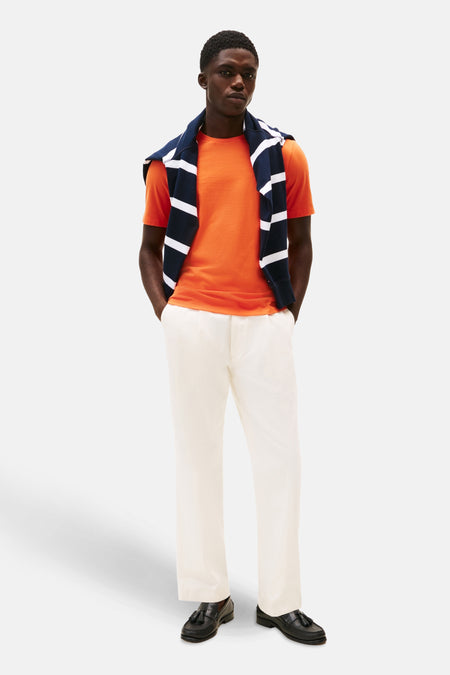 T-shirt à manches courtes orange de TOMMY HILFIGER avec un pull rayé sur les épaules.