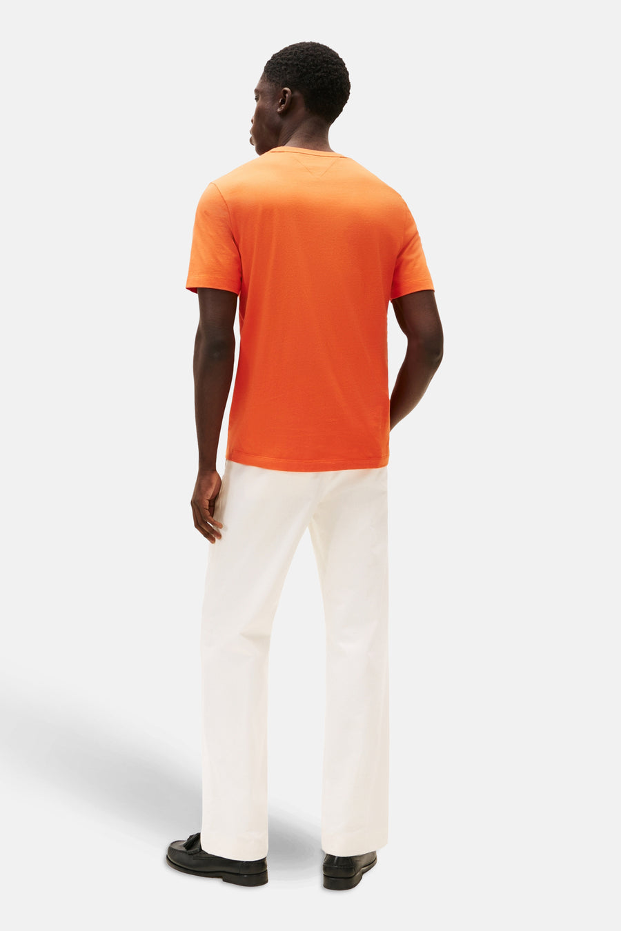 T-shirt à manches courtes orange de Tommy Hilfiger, porté avec un pantalon blanc, vue de dos.

