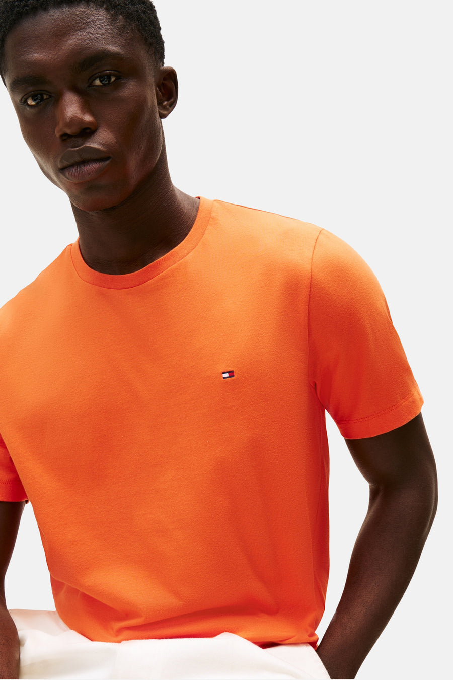 T-shirt orange à manches courtes de TOMMY HILFIGER, porté par un homme, avec le logo sur la poitrine.