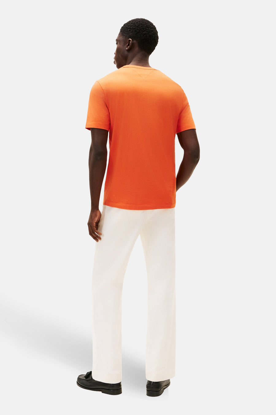 T-shirt orange à manches courtes de TOMMY HILFIGER, porté avec un pantalon blanc et des mocassins noirs, vue de dos.