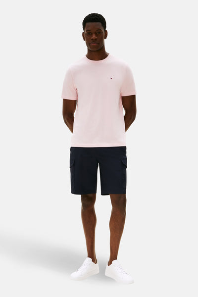 T-shirt rose à manches courtes de TOMMY HILFIGER, porté avec un short cargo bleu marine et des baskets blanches.