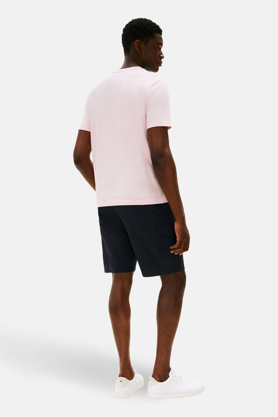 T-shirt à manches courtes rose de TOMMY HILFIGER, porté avec un short cargo bleu marine et des baskets blanches.
