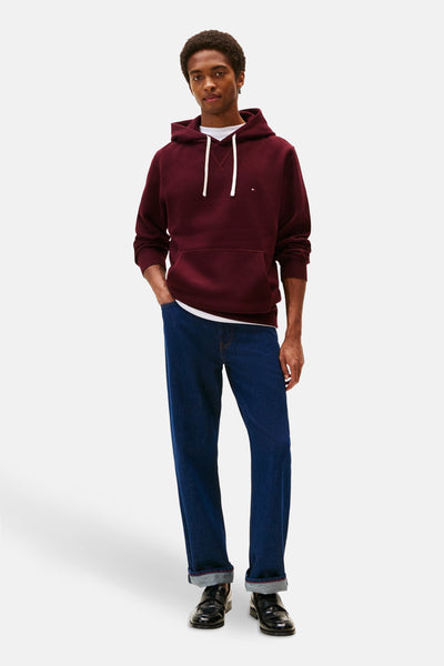 Bordeaux hoodie van Tommy Hilfiger, gedragen met een wit T-shirt en een donkerblauwe jeans.
