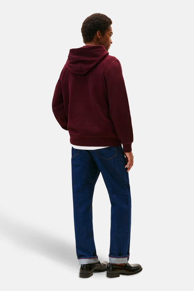 Bordeaux hoodie van TOMMY HILFIGER, gedragen met een blauwe jeans en zwarte loafers.