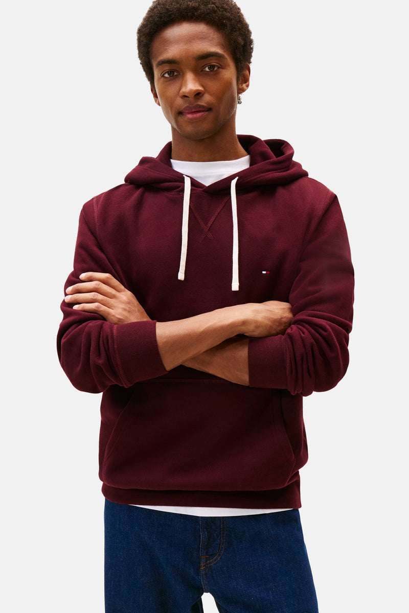 Bordeaux hoodie van Tommy Hilfiger, gedragen met een wit T-shirt en een blauwe jeans.