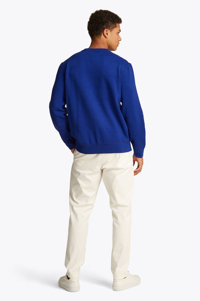 Sweat col rond bleu de TOMMY HILFIGER, porté avec un pantalon beige et des chaussures assorties, vue de dos.
