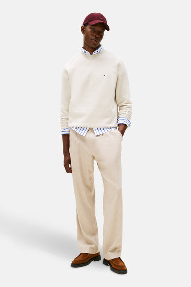 Ecru ronde hals sweatshirt van TOMMY HILFIGER, gedragen over een gestreept overhemd, met een beige broek.