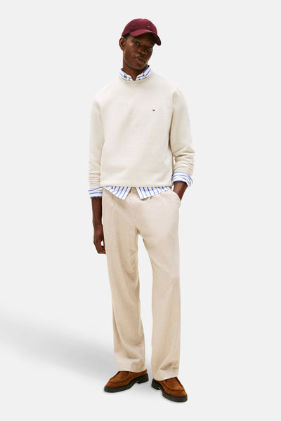 Ecru ronde hals sweatshirt van TOMMY HILFIGER, gedragen over een gestreept overhemd, met een beige broek.