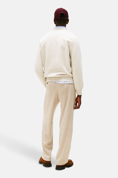 Ecru ronde hals sweatshirt van Tommy Hilfiger, gedragen met een gestreept overhemd en een beige broek.