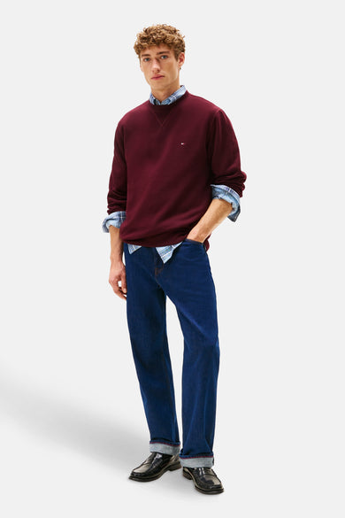 Rode rondehals sweatshirt van Tommy Hilfiger, gedragen met een geruit overhemd en een spijkerbroek.