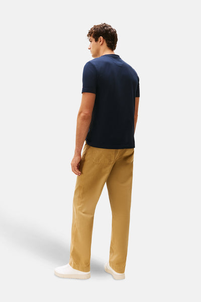 Marineblaues T-Shirt mit kurzen Ärmeln von TOMMY HILFIGER, getragen mit einer beigen Chinohose und weißen Turnschuhen, Rückansicht.