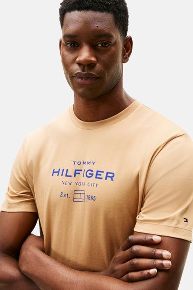 Beige T-shirt met korte mouwen van TOMMY HILFIGER met blauw logo op de voorkant.