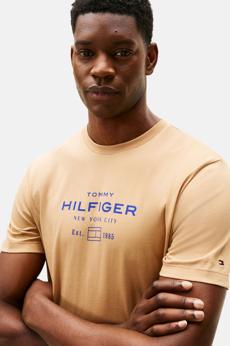 Beige T-shirt met korte mouwen van TOMMY HILFIGER met blauw logo op de voorkant.