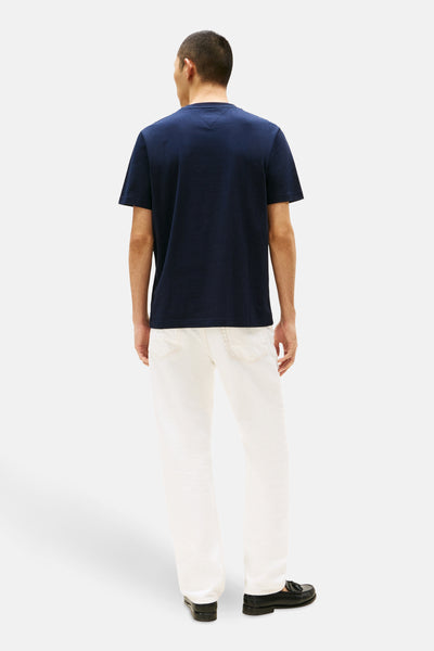 T-shirt bleu à manches courtes de TOMMY HILFIGER, porté avec un pantalon blanc et des mocassins noirs, vue de dos.
