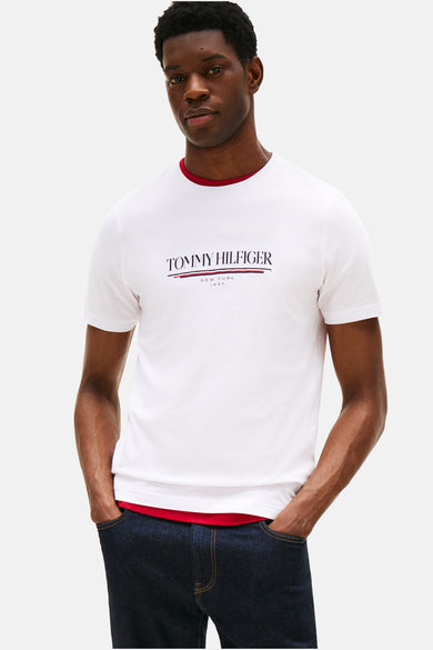 T-shirt à manches courtes blanc de TOMMY HILFIGER, avec logo sur le devant, porté avec un jean foncé.