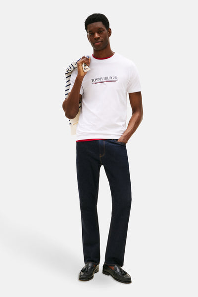 T-shirt blanc à manches courtes de Tommy Hilfiger, porté avec un jean et des mocassins à glands, veste rayée sur l'épaule.